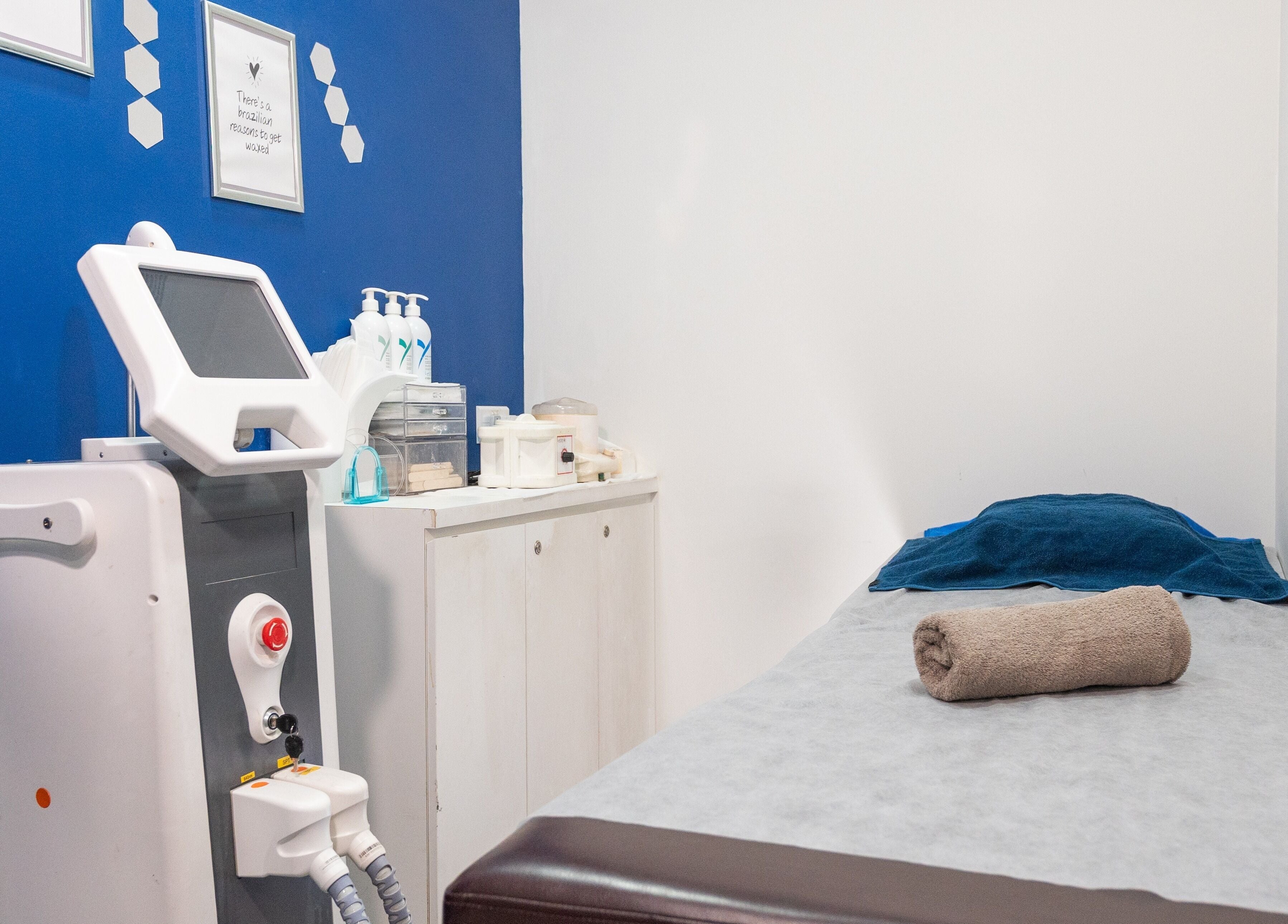 Cozy treatment room at Wax Factor Orchard Central, Singapore with modern equipment, bed, and towels.