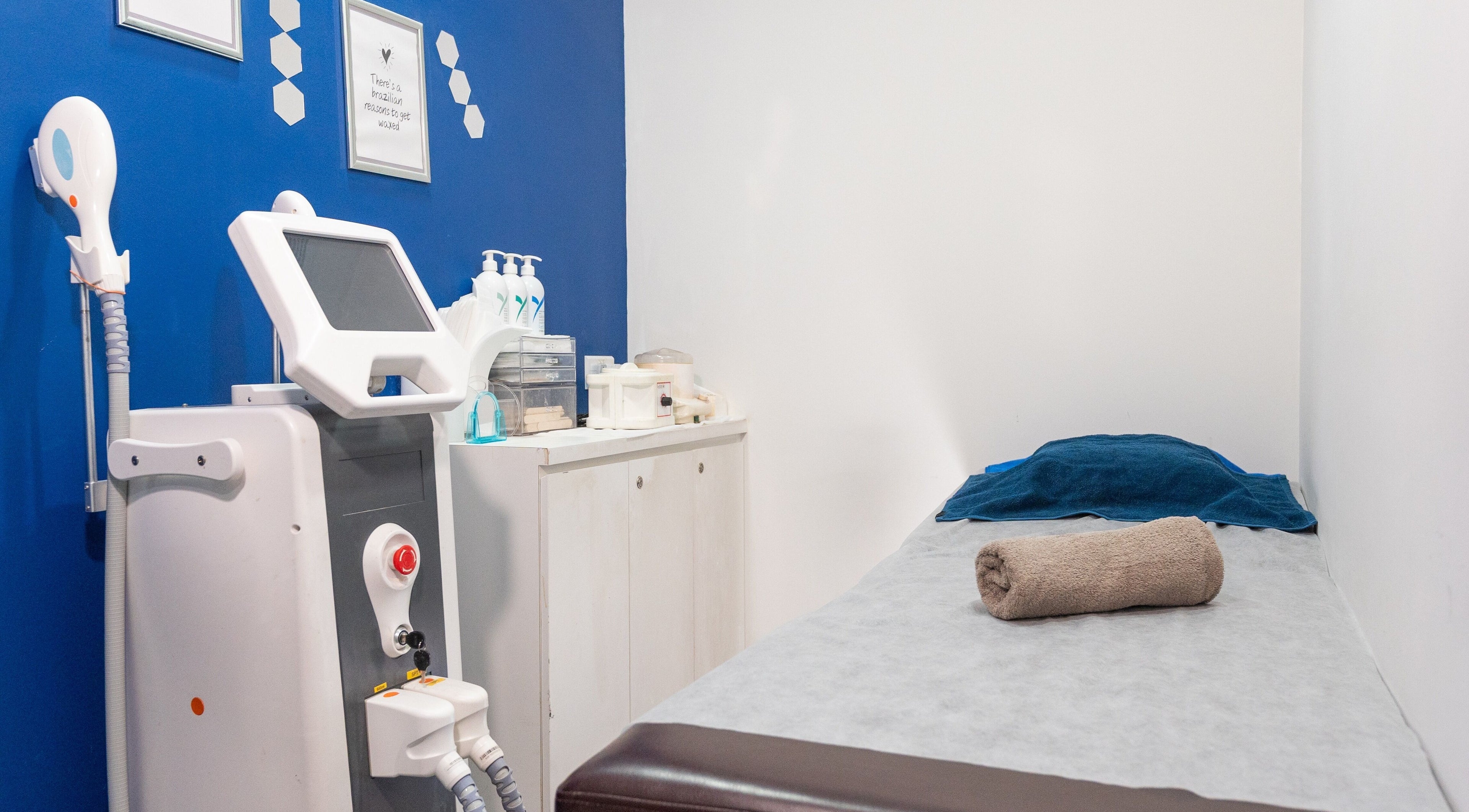 Cozy treatment room at Wax Factor Orchard Central, Singapore with modern equipment, bed, and towels.