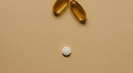 Two softgel capsules and a tablet on a beige background at Pharmable, London, GB.