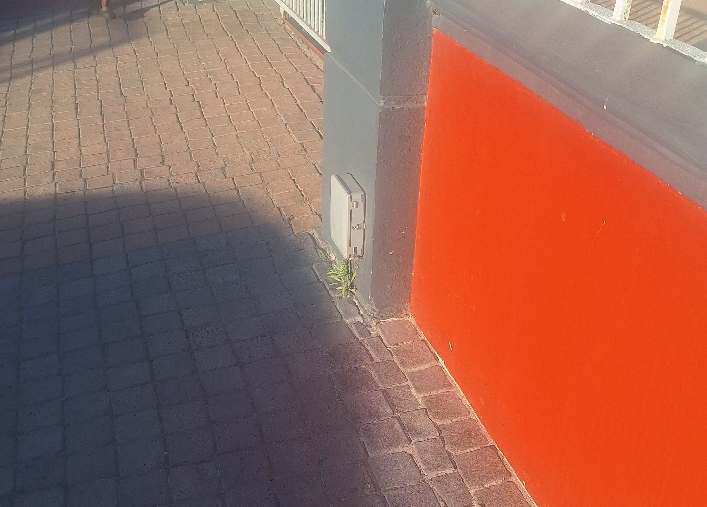 Vibrant red wall and textured pavement outside Nene's Beauty Mobile Spa in Cape Town, Western Cape, ZA.