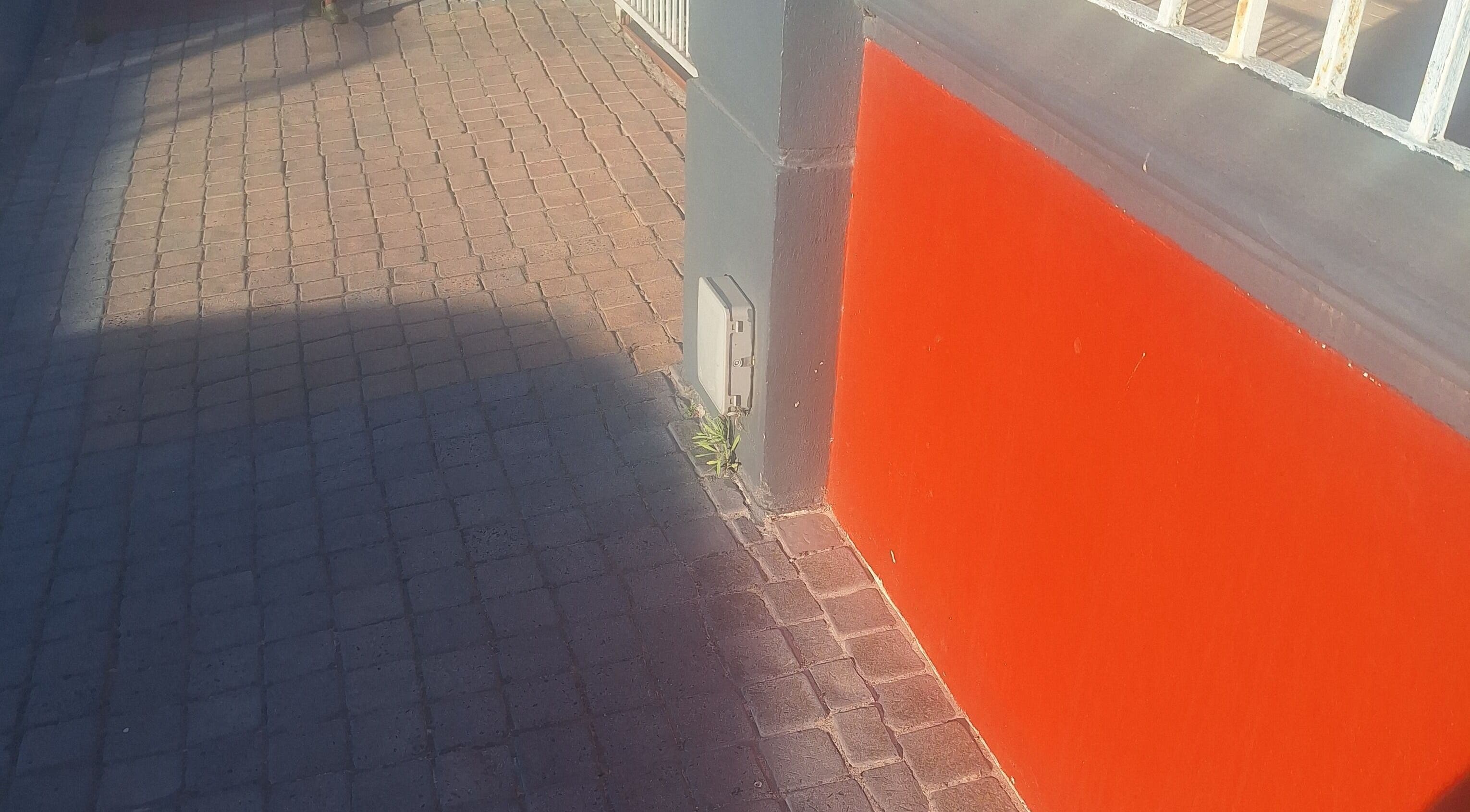 Vibrant red wall and textured pavement outside Nene's Beauty Mobile Spa in Cape Town, Western Cape, ZA.