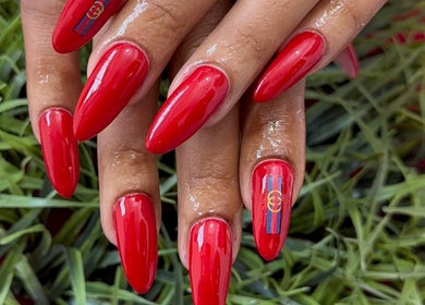 Glossy red manicure designed by Noelin Artistry Studio in Pretoria, Gauteng, ZA amidst lush greenery.