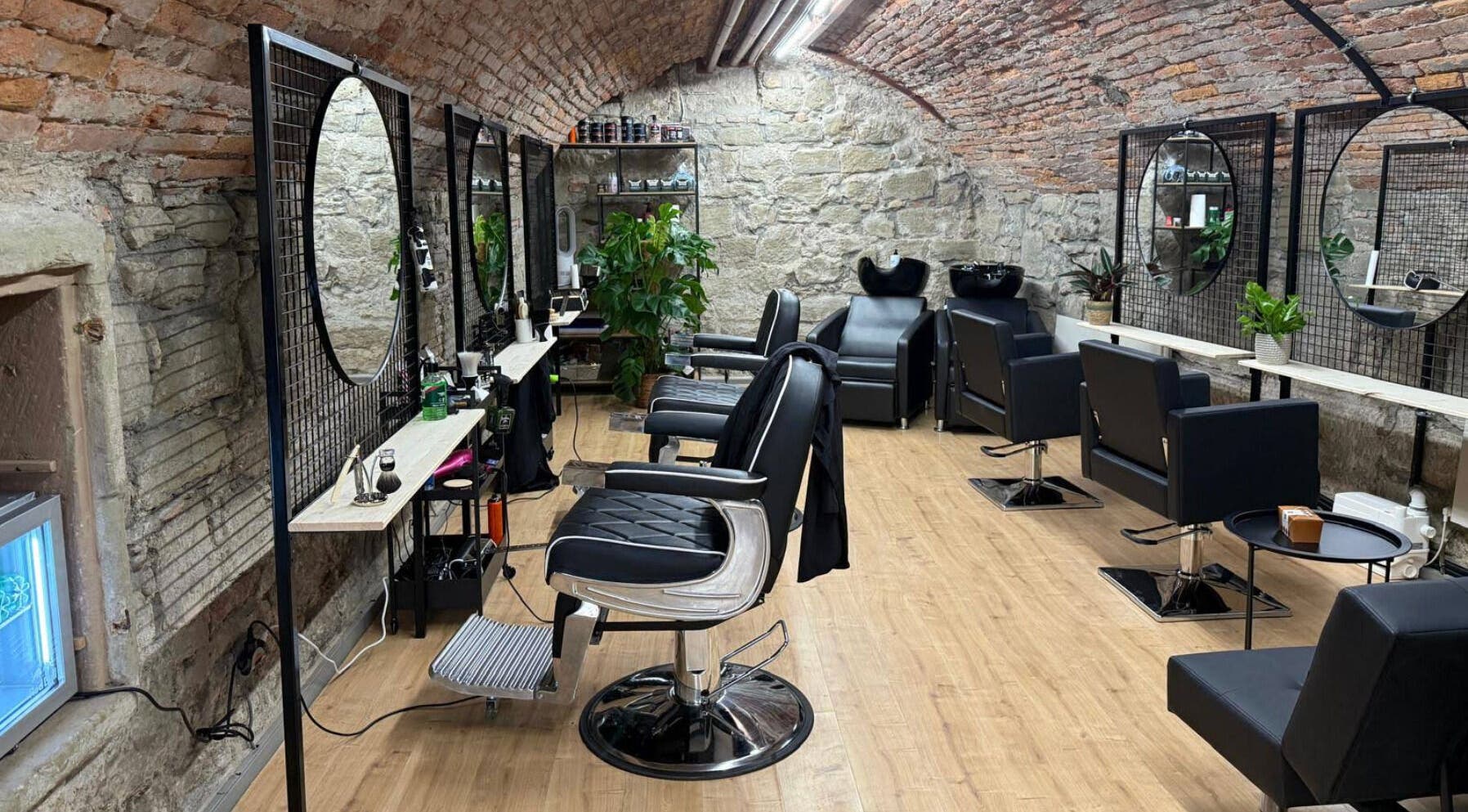 Interno elegante di Sa-Rc Italia Coiffeur Bern, in Bern, Bern, CH, con sedie nere e muri in pietra.