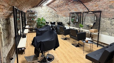 Interno rustico ed elegante di Sa-Rc Italia Coiffeur Bern a Bern, Bern, CH con poltrone nere e specchi circolari.