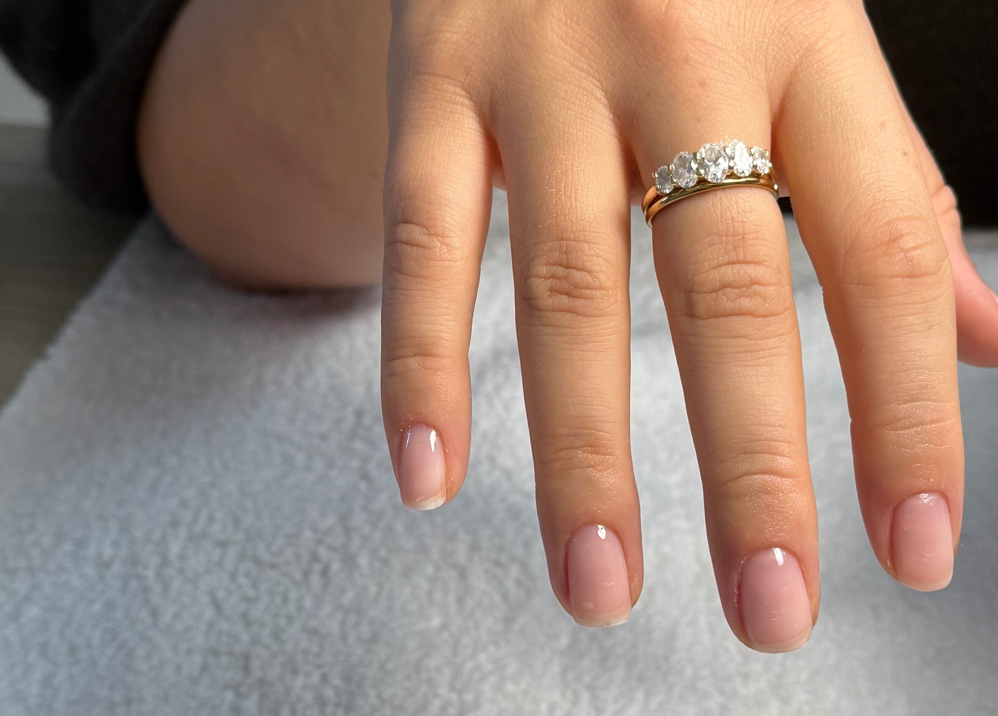 Elegant manicure at BAJE STUDIO in Burgess Hill, England, GB. Showcasing neatly polished nails with a gold ring.