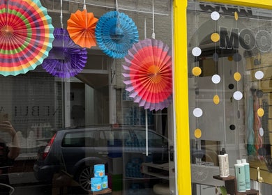 Colorful paper decorations in the window of Pins & Curls, Weston-super-mare, England, GB.