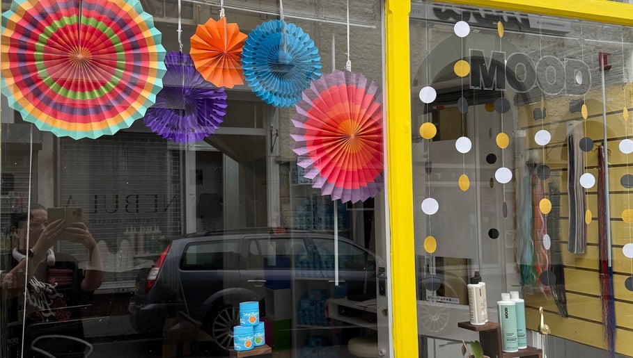 Vibrant window display at Pins & Curls, Weston-super-mare, England, GB showcasing colorful paper decorations.