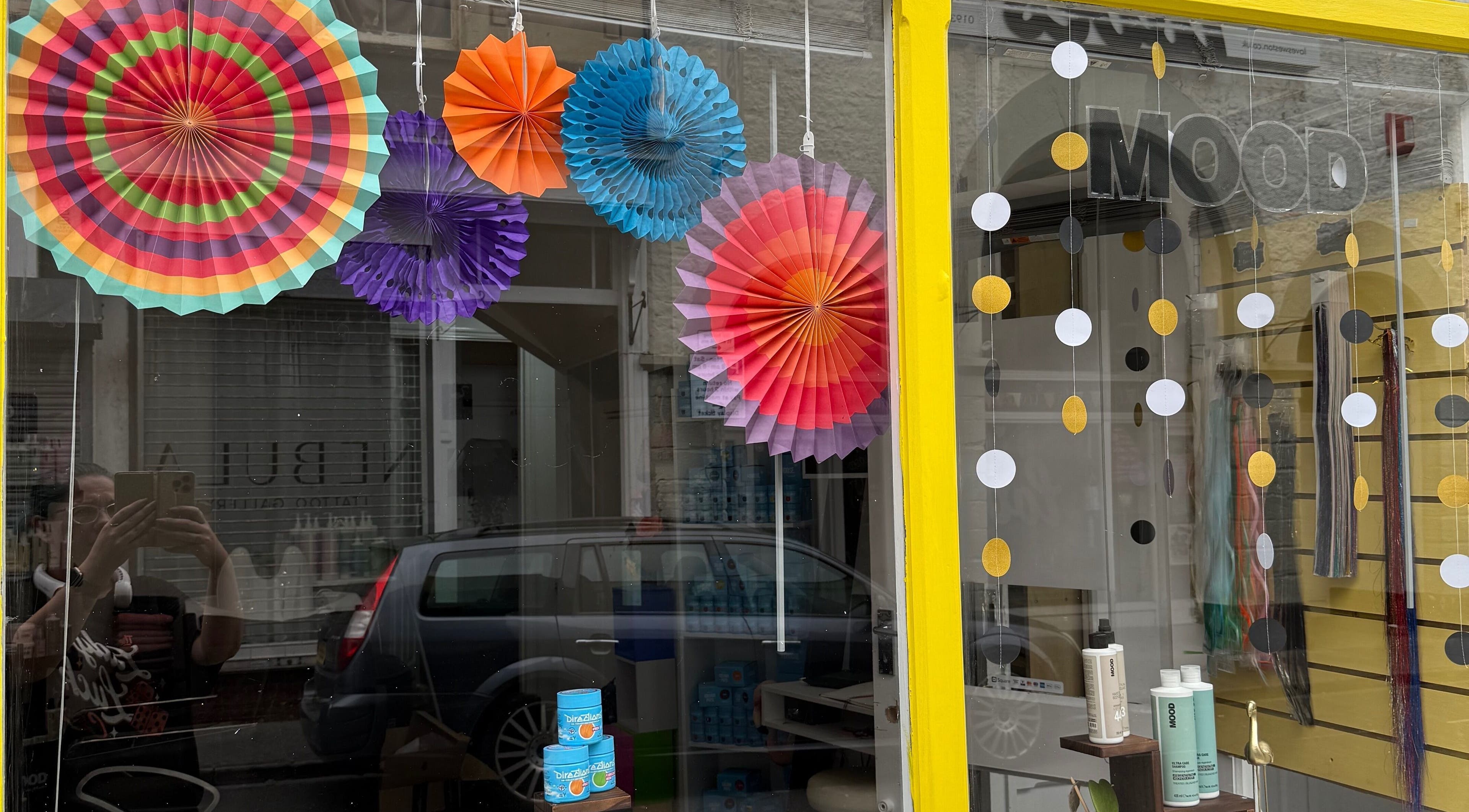 Colorful paper decorations adorn Pins & Curls window in Weston-super-mare, England, GB, adding a festive touch.