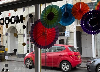Colorful paper decor hanging in Pins & Curls window, Weston-super-Mare, England, GB.