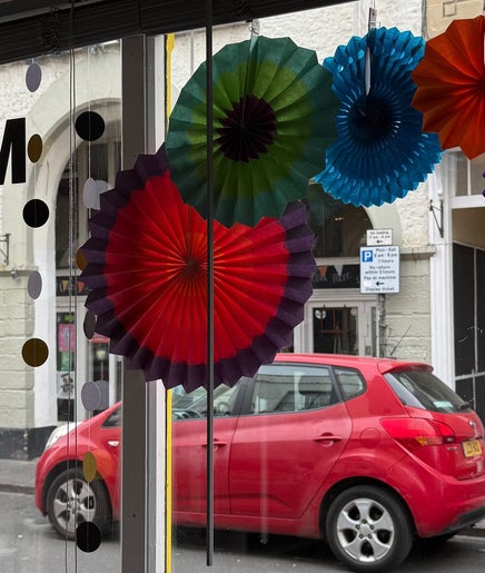 Colorful paper decor hanging in Pins & Curls window, Weston-super-Mare, England, GB.