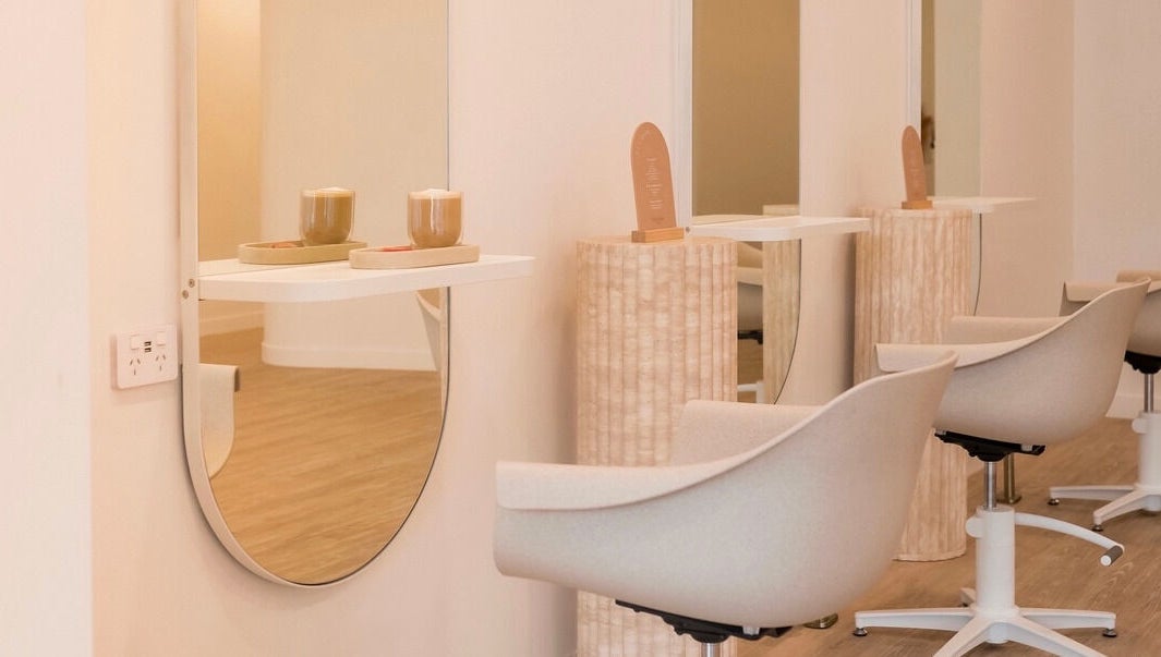 Modern salon chairs and mirrors at Cocoon Hair in Bracken Ridge, Queensland, AU, offering a serene ambiance.