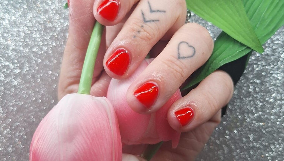 Vibrant red manicured nails with delicate tattoos at Nailed it! By Rachel, Irchester, England, GB.