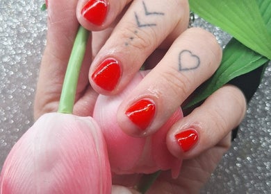 Vibrant red manicured nails with delicate tattoos at Nailed it! By Rachel, Irchester, England, GB.
