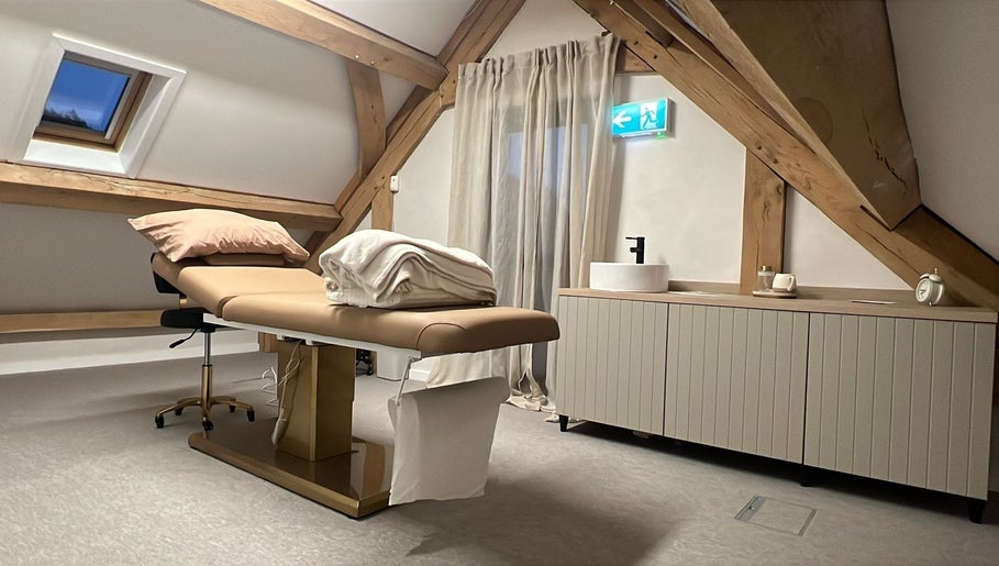 Elegant treatment room at Tommo’s Treatments - Luxe Barn, Tickenham, England, GB with a massage table and wooden beams.
