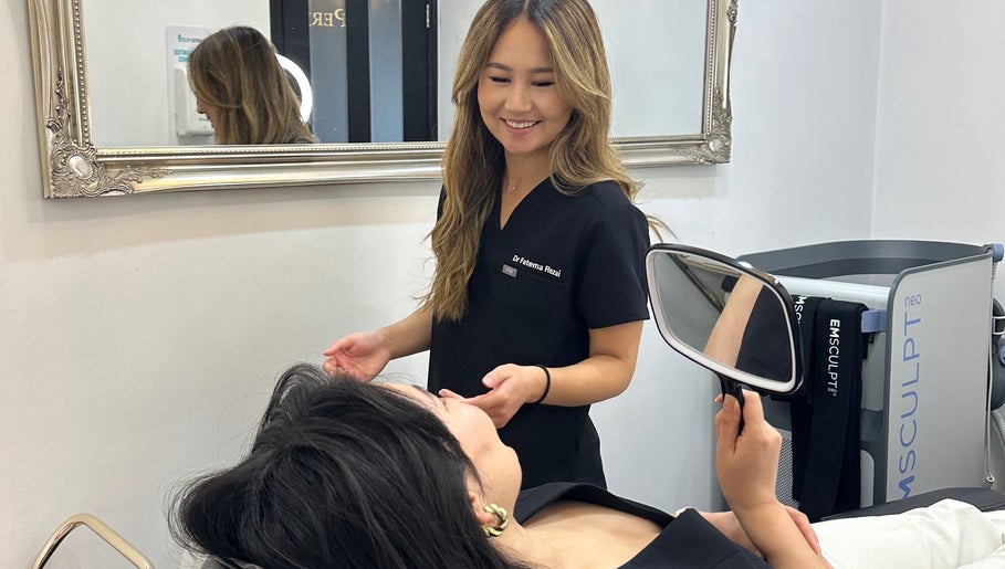 Professional consultation at Rezai Aesthetics, London, England, GB with patient holding a mirror.