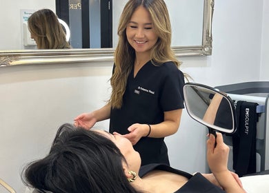 Professional consultation at Rezai Aesthetics, London, England, GB with patient holding a mirror.