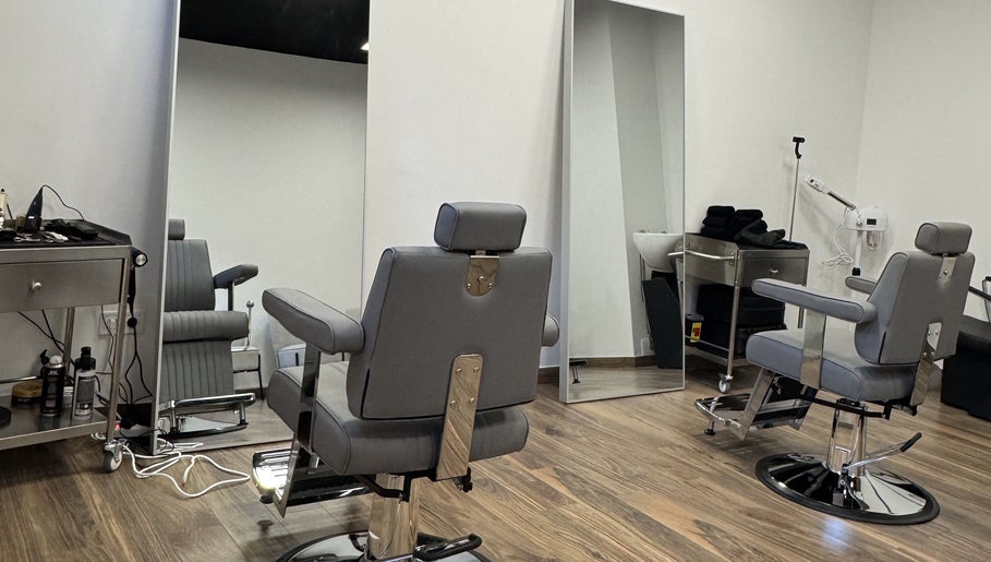 Interior moderno da UNIQ Barbershop em Póvoa De Varzim, Porto, PT, com cadeiras de barbearia elegantes.
