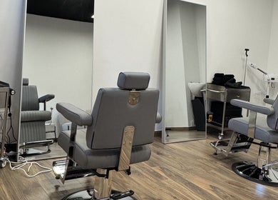 Interior moderno da UNIQ Barbershop em Póvoa De Varzim, Porto, PT, com cadeiras de barbearia elegantes.