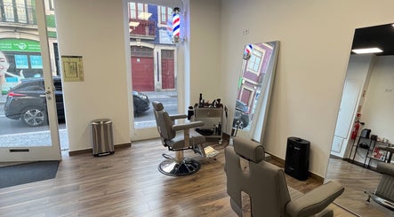 Interior moderno do UNIQ Barbershop em Póvoa De Varzim, Porto, PT, com cadeiras confortáveis e espelho grande.