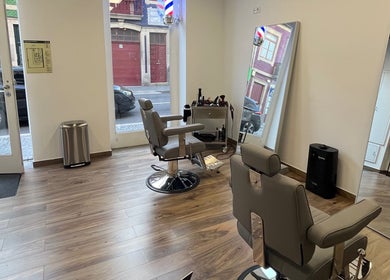 Cadeiras modernas no UNIQ Barbershop em Póvoa De Varzim, Porto, PT, com espelho grande e piso de madeira.