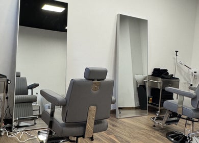 Interior moderno do UNIQ Barbershop em Póvoa De Varzim, Porto, PT, com cadeiras de barbeiro elegantes e espelhos grandes.