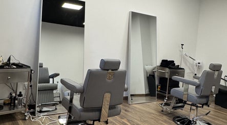 Interior moderno do UNIQ Barbershop em Póvoa De Varzim, Porto, PT, com cadeiras de barbeiro elegantes e espelhos grandes.