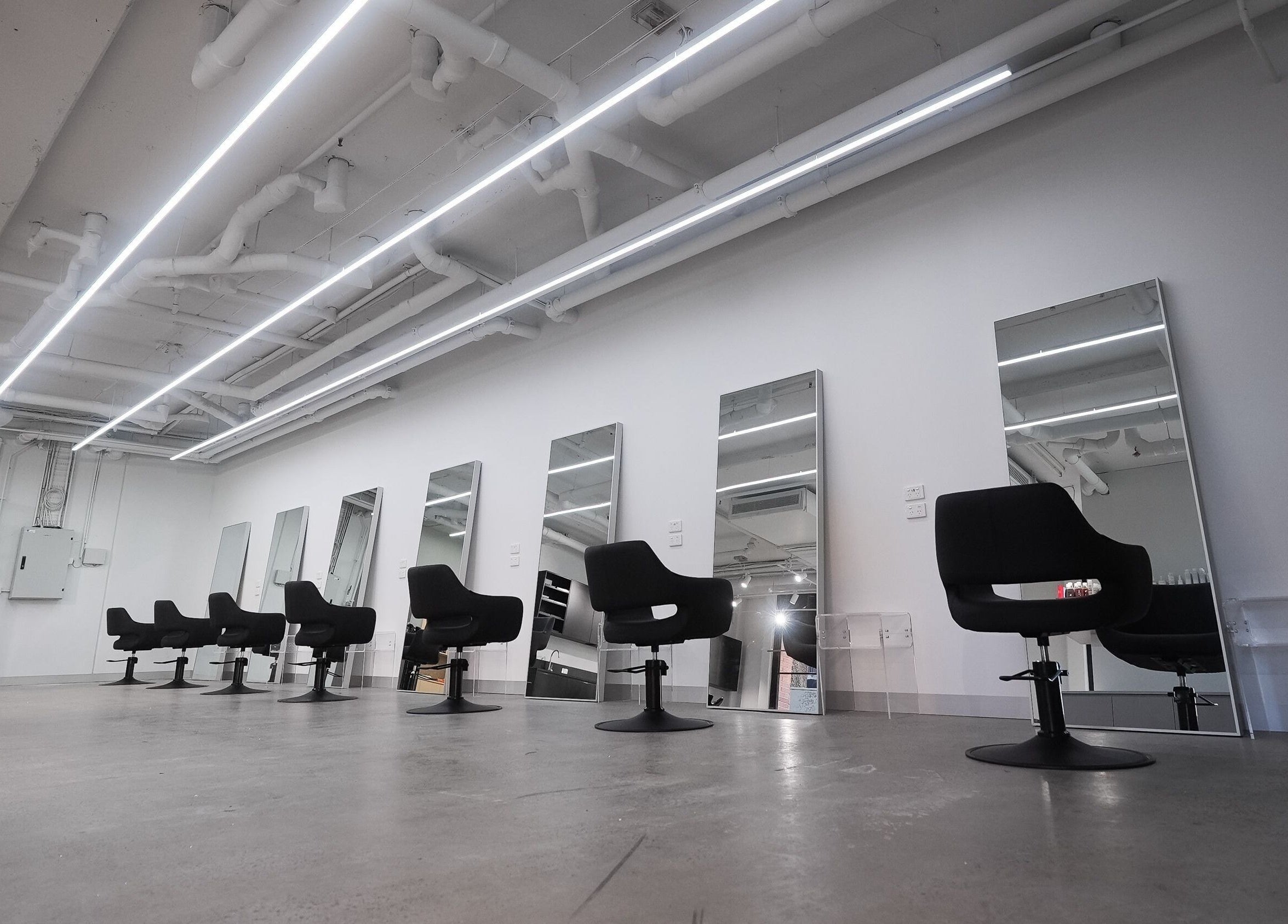Modern salon interior at ASSORT HAIR PTY LTD, Melbourne, Victoria, AU, featuring stylish chairs and mirrors.