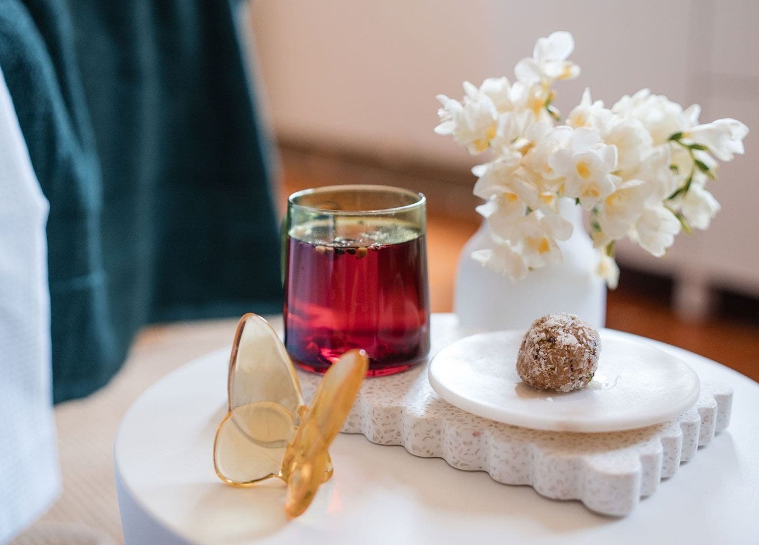 Relaxing scene at The Peaceful Skin Co, Melbourne, Victoria, AU, featuring a drink, treat, and flowers.