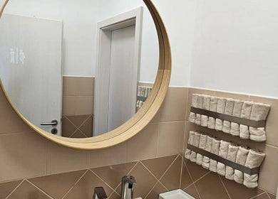 Koupelna v ŠŤABAJZNA - přírodní organický kosmetický salon, Poděbrady, CZ s velkým kulatým zrcadlem a ručníky.