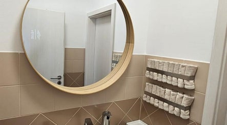 Koupelna v ŠŤABAJZNA - přírodní organický kosmetický salon, Poděbrady, CZ s velkým kulatým zrcadlem a ručníky.