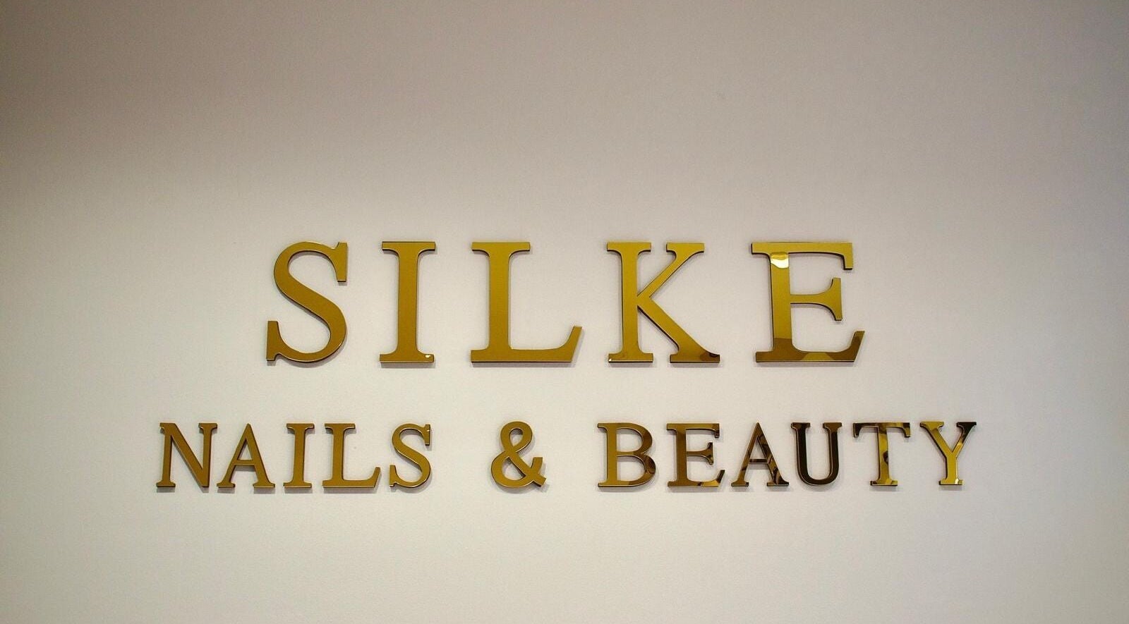 Gouden logo van Silke Nails & Beauty op de muur te Bolsward, Friesland, NL.