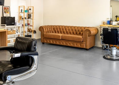 Modern barber interior at Dapper Man London, West Wollongong, New South Wales, AU, featuring vintage chairs and a leather sofa.