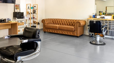 Modern barber interior at Dapper Man London, West Wollongong, New South Wales, AU, featuring vintage chairs and a leather sofa.