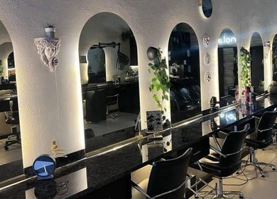 Modern salon interior at Tella The Hybrid Stylist, Pretoria, Gauteng, ZA, featuring sleek black chairs and mirrors.