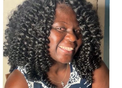 Smiling woman with curly hair at Crownedbycassie, Lauderhill, Florida, US.