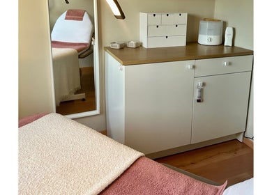 Sfeervolle behandelkamer bij Puur ‘L by Lauren in Bornem, Vlaanderen, BE, met comfortabele stoel en opbergkast.