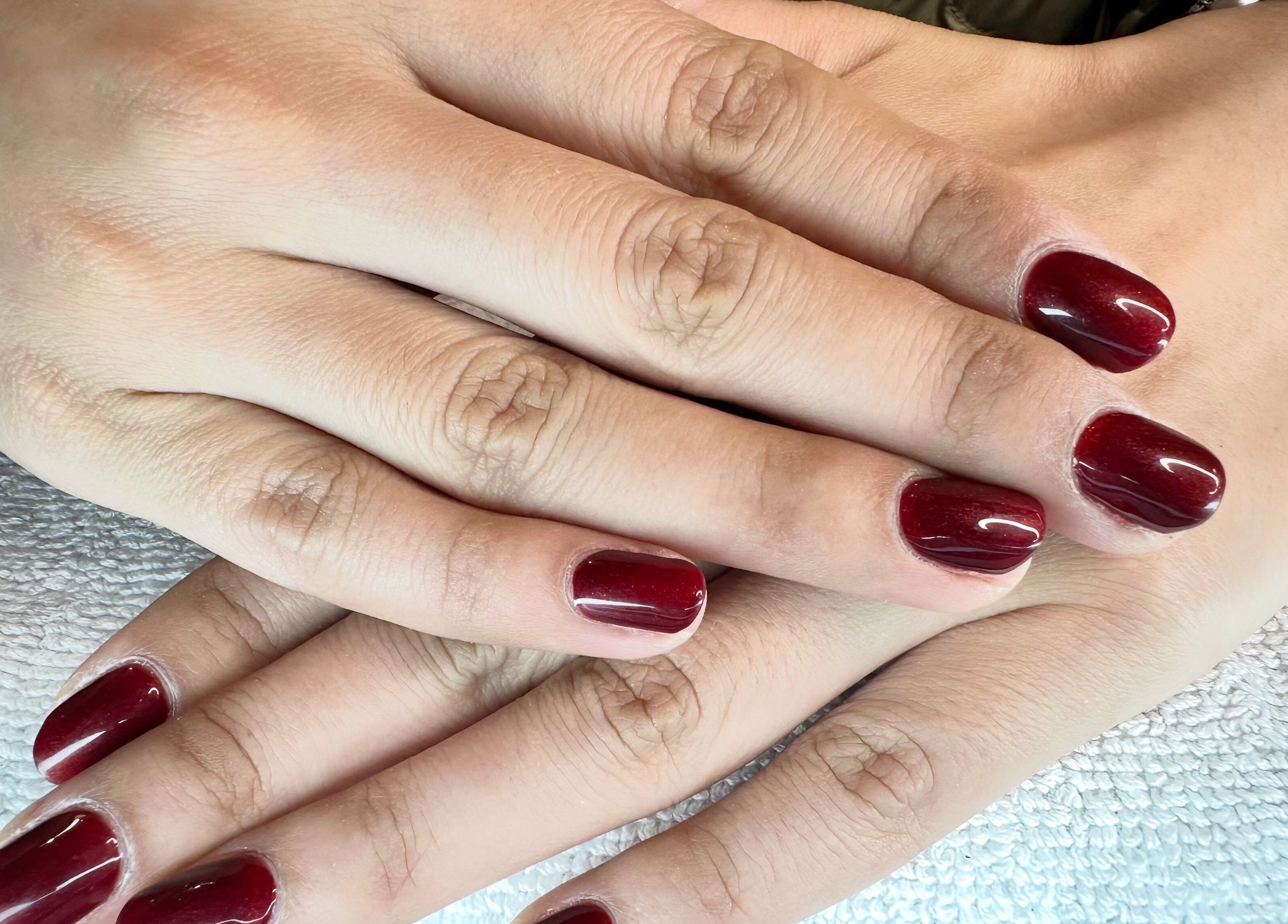 Manicured hands with crimson nails at Tatabeautyhouse, Canterbury, England, GB.