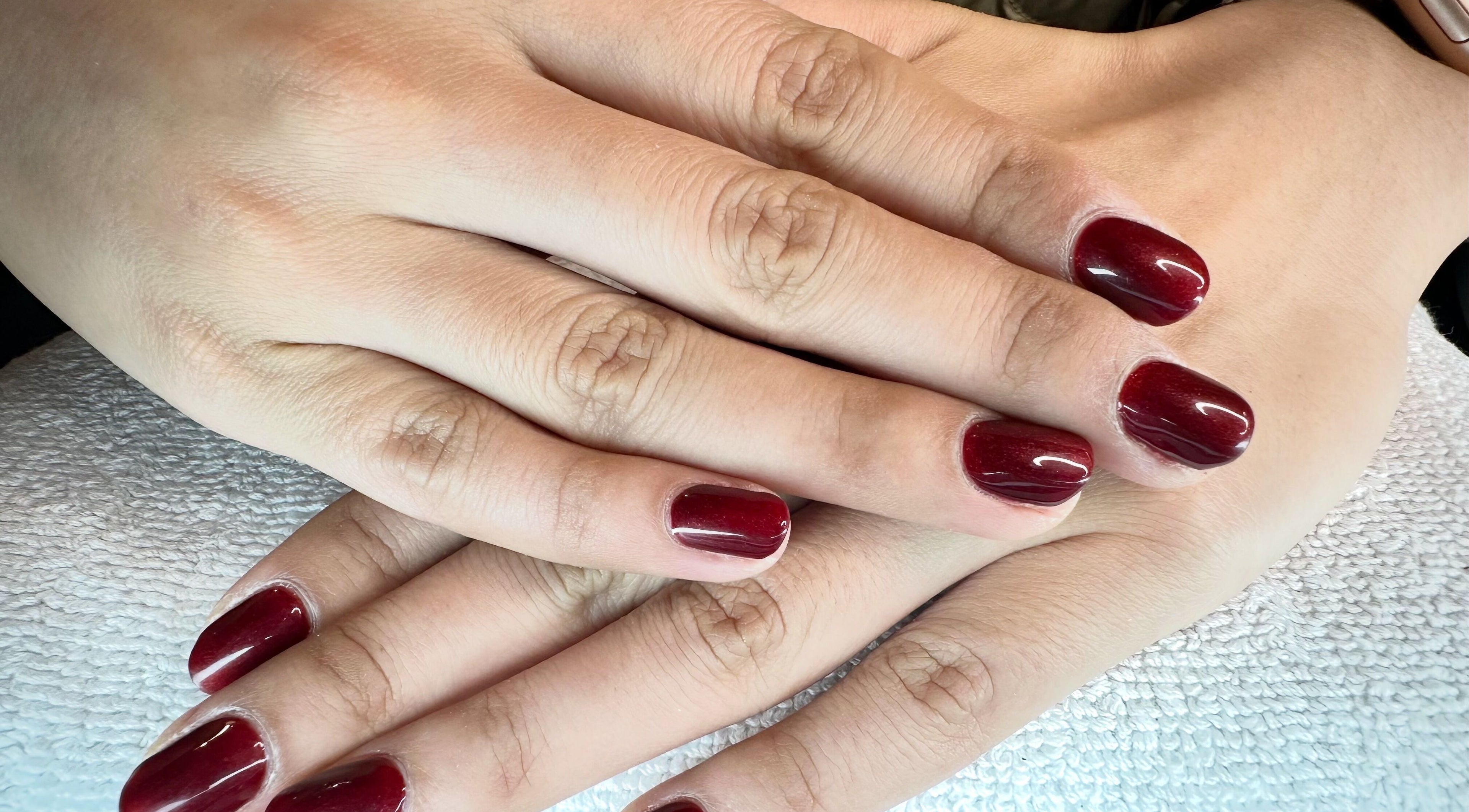 Manicured hands with crimson nails at Tatabeautyhouse, Canterbury, England, GB.