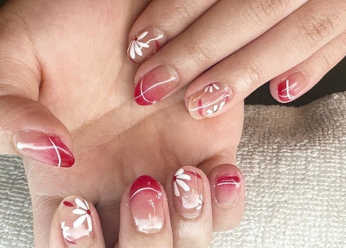 Elegant floral nail art in red and white at Tatabeautyhouse, Canterbury, England, GB.