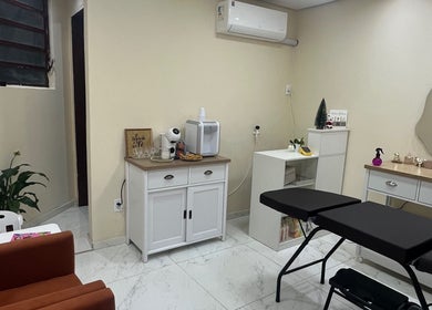 Sala aconchegante do Ateliê Milene Ribeiro, Rio Grande do Sul, BR, com sofá, plantas e equipamentos de beleza.