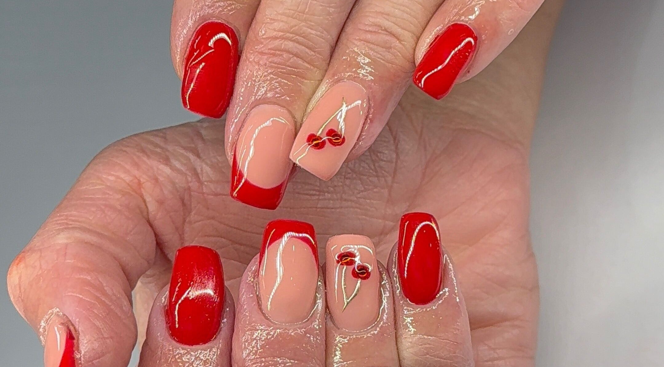 Stylish red and nude cherry nail art at Nikki Nails, Llansamlet, Wales, GB.