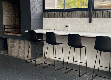 Modern lounge area at Braids by Zonke, Gqeberha, Eastern Cape, ZA with bar stools and brick decor.