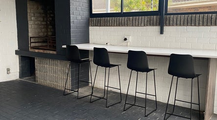 Modern lounge area at Braids by Zonke, Gqeberha, Eastern Cape, ZA with bar stools and brick decor.