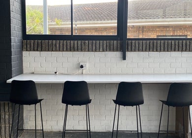 Modern seating area at Braids by Zonke, Gqeberha, Eastern Cape, ZA with sleek black chairs and white counter.