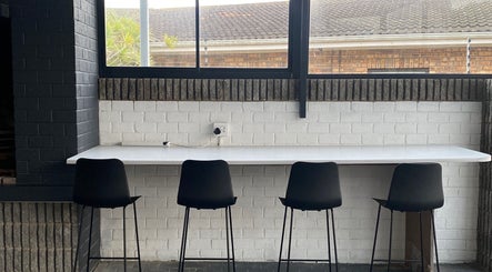 Modern seating area at Braids by Zonke, Gqeberha, Eastern Cape, ZA with sleek black chairs and white counter.