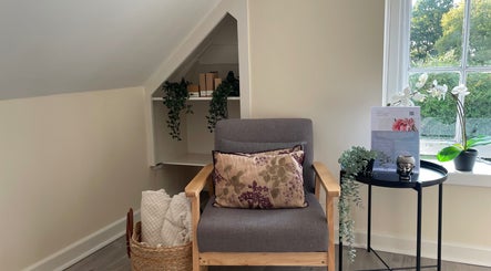 Cozy chair with cushions at Louisa Sales Malia Organics, Christchurch, Hampshire Dorset, GB, near a sunlit window.