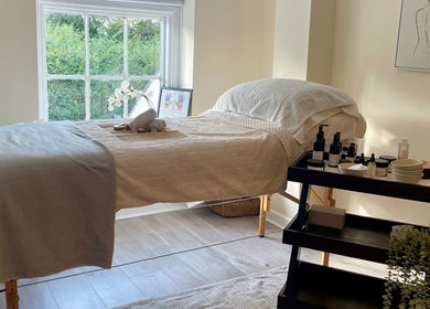 Relaxing massage room at Louisa Sales Malia Organics, Christchurch, Hampshire, GB, featuring a cozy bed with products.