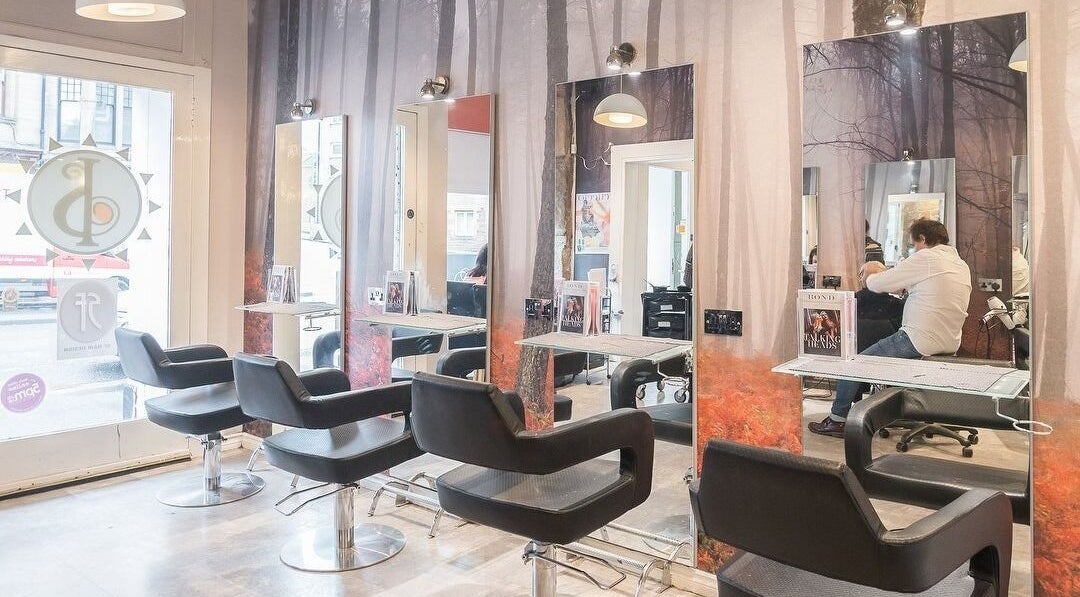 Modern hairdressing station at Iain Stewart Hairdressing Ltd in Paisley, Scotland, GB with stylish chairs and mirrors.
