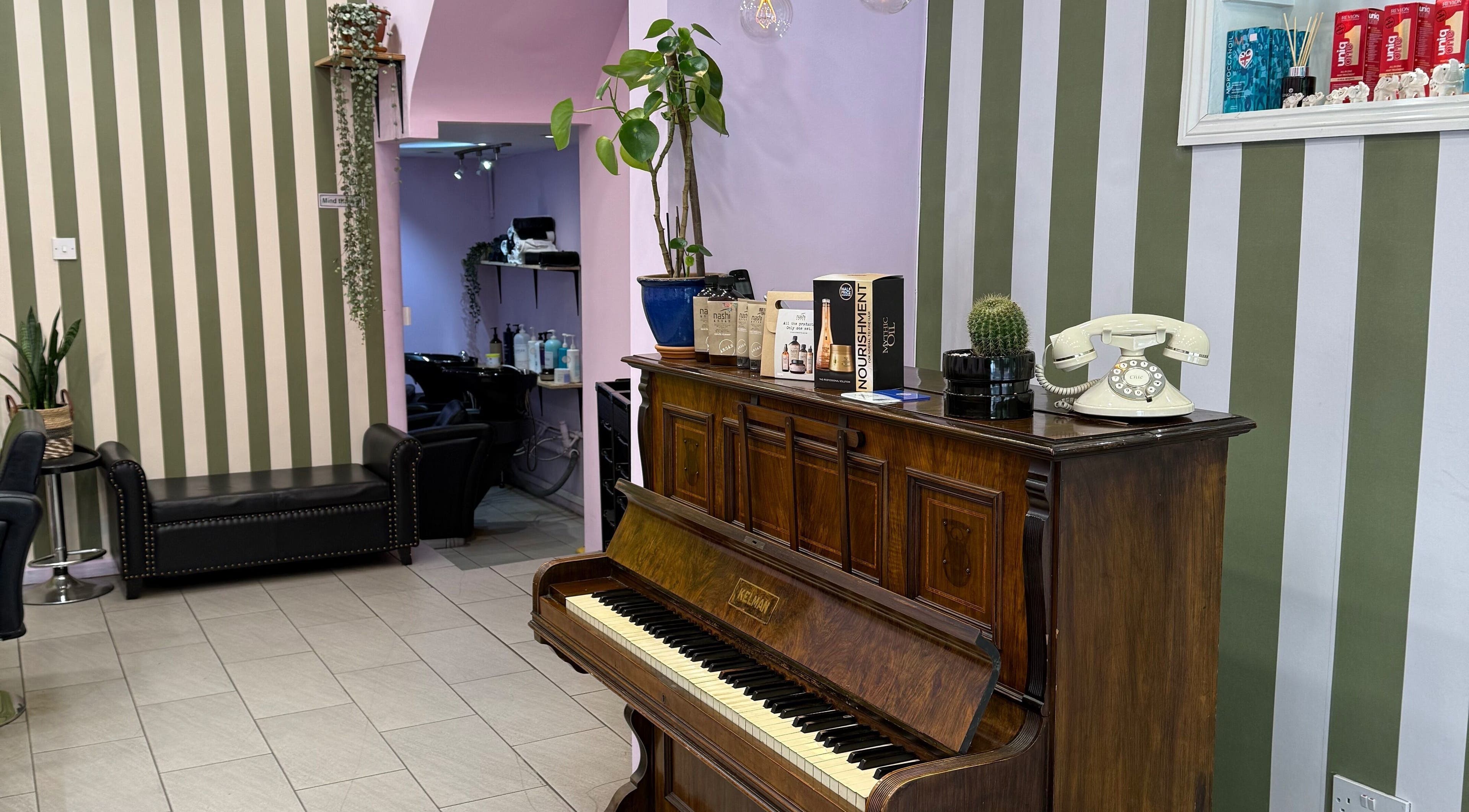 Cut & Craft salon in London, England, GB featuring vintage decor with piano and green plants.