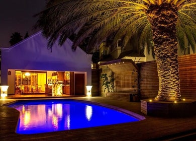 Evening poolside view at Peau Aesthetics, Germiston, Gauteng, ZA with illuminated palm tree and elegant lounge.